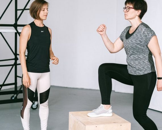 Fitness coach guides a woman in workout indoors. Focus on exercise and healthy lifestyle.